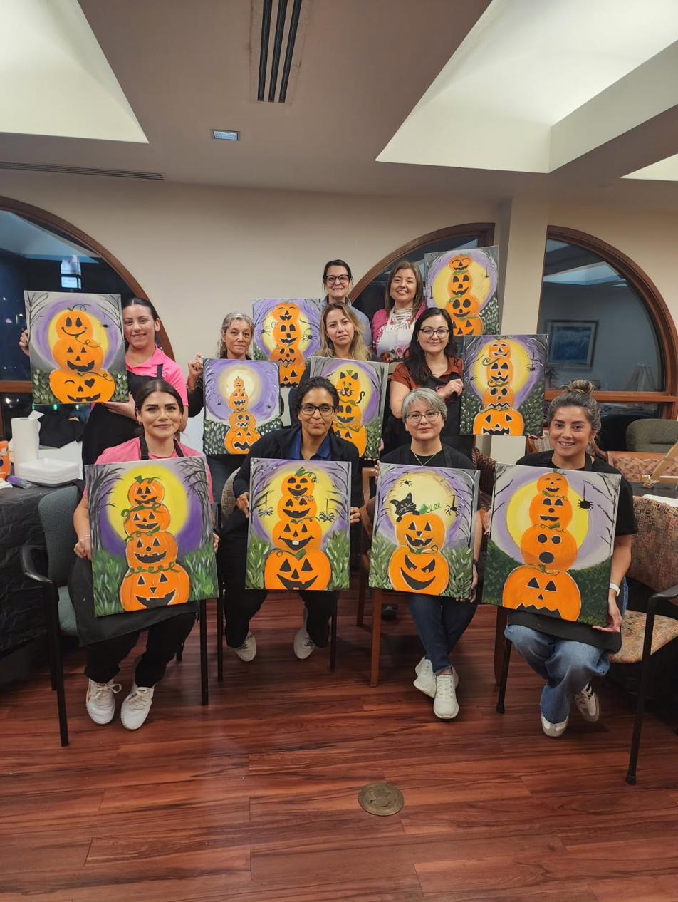 Guests holding stacked pumpkin paintings